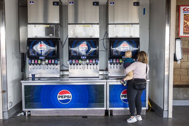 A woman with a child fills a cup with Pepsi products in the food court of a Costco warehouse