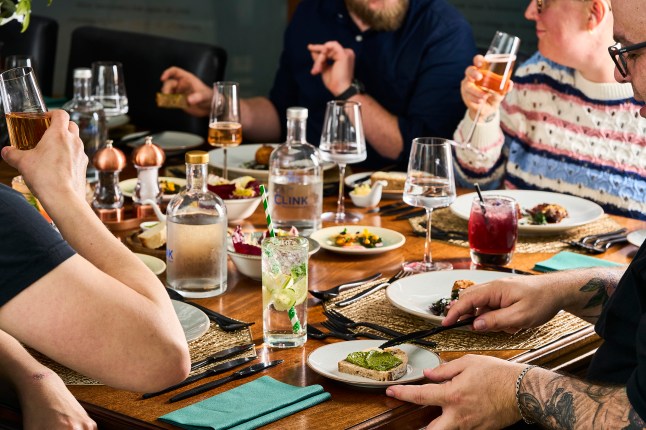 A table full of food and drink and people dining at The Clink