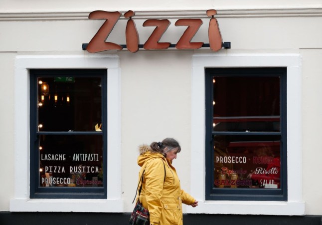A photo of a woman walking past a Zizi restaurant