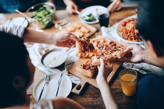 Close up of a young group of friends passing and serving food while enjoying together.