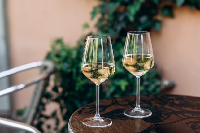 Two glass of white wine on a table in a bar on the street in a European city.