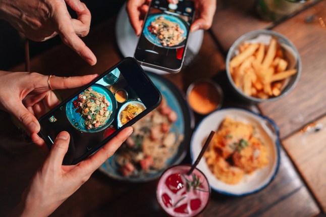 Close-up shot of group of friends using their smartphones to take pictures of the food on the table
