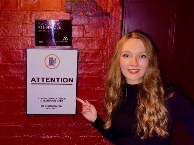 Courtney Pochin at The Spy Bar pointing to a no photos sign