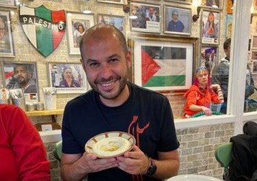 Amro Tabari smiles and holds a bowl of hummus
