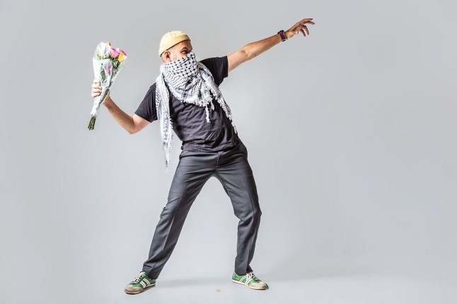 Amro Tabari wears a keffiyeh while holding a bouquet of flowers in one hand